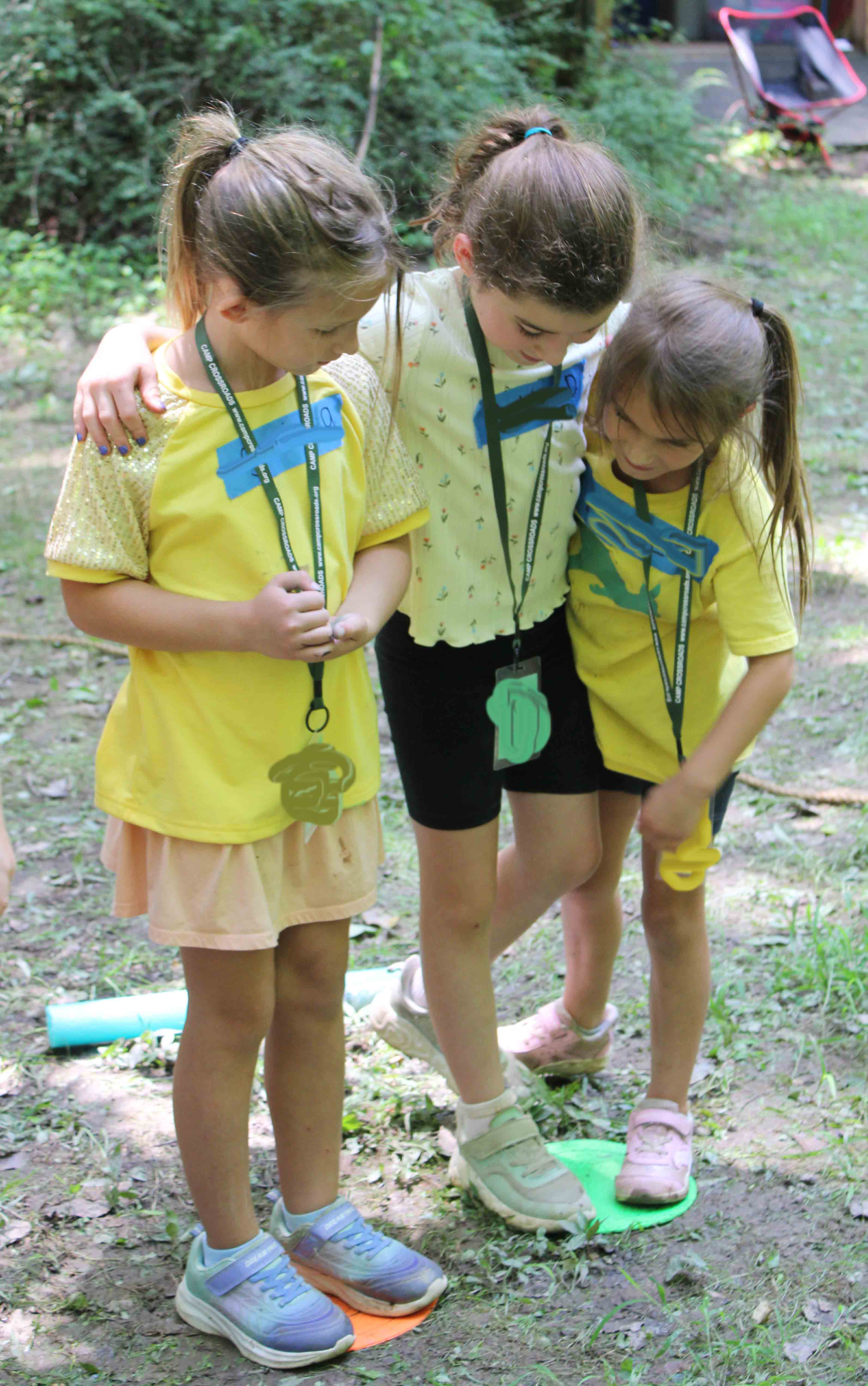 Three campers working together and supporting each other through a balance activity on the outdoor challenge course.