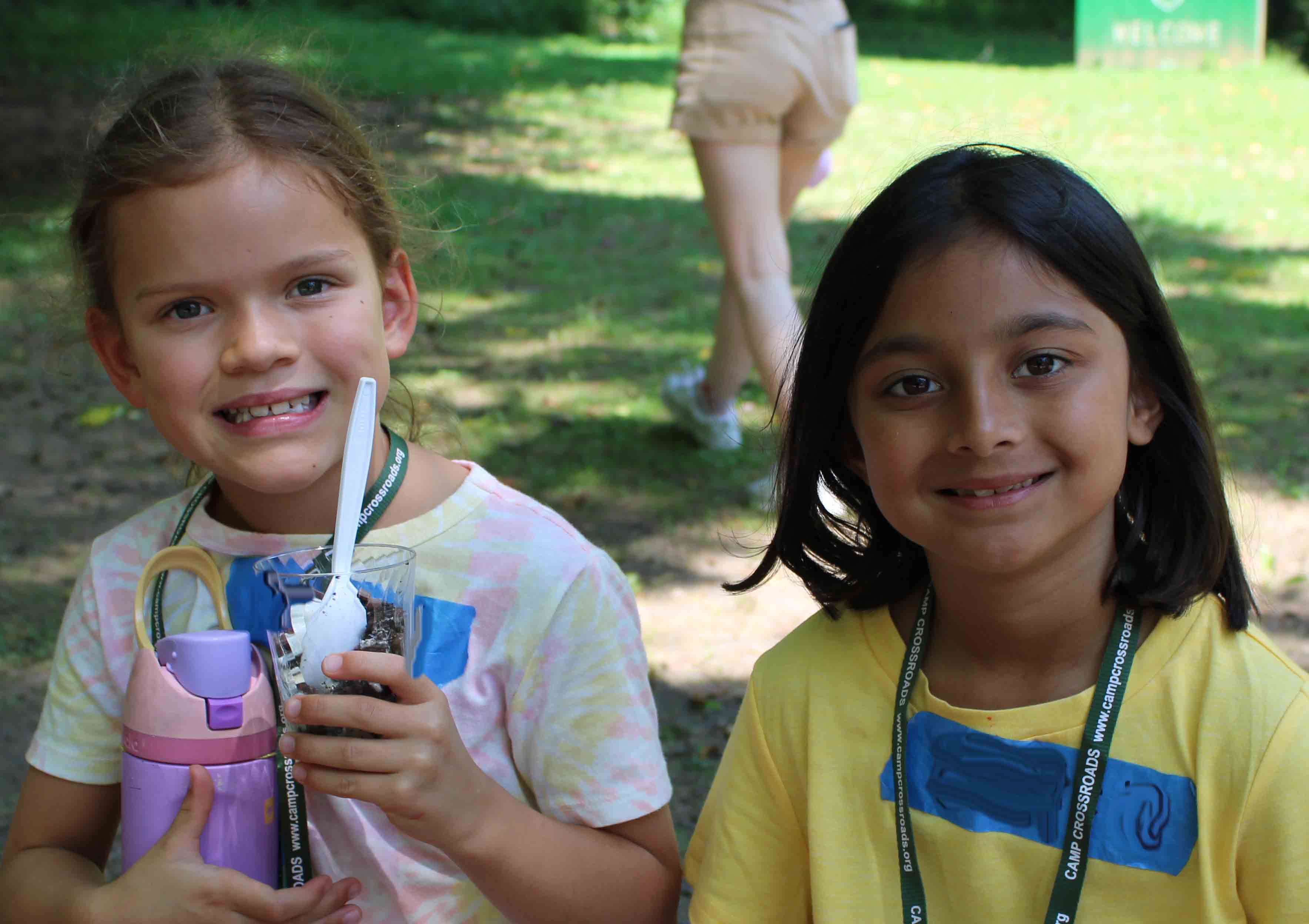 Two smiling campers from the Bats unit enjoying their cold ice cream treats outdoors.
