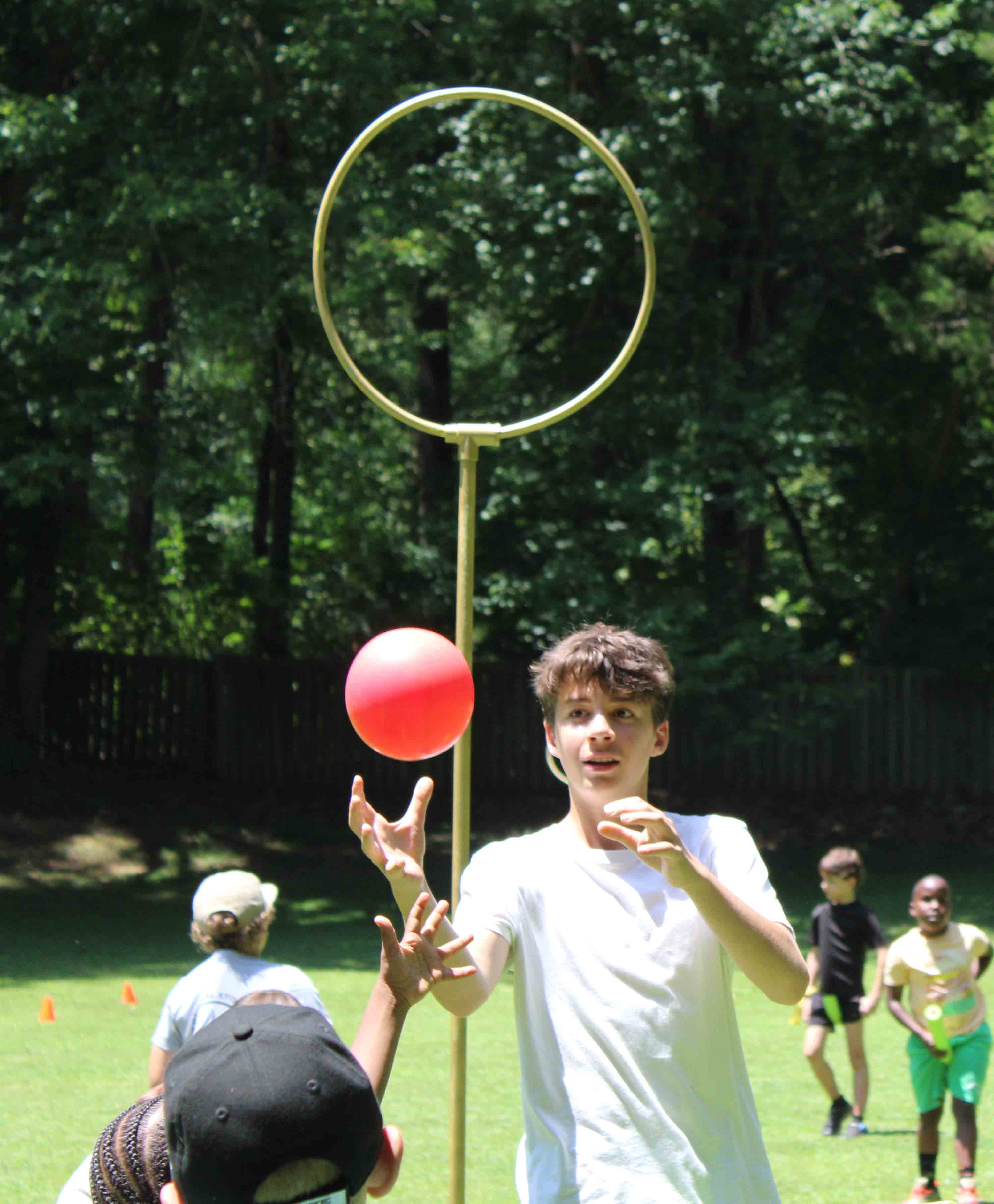 A camper from the Rangers unit leaping into the air to catch a red ball during a competitive Quidditch game.