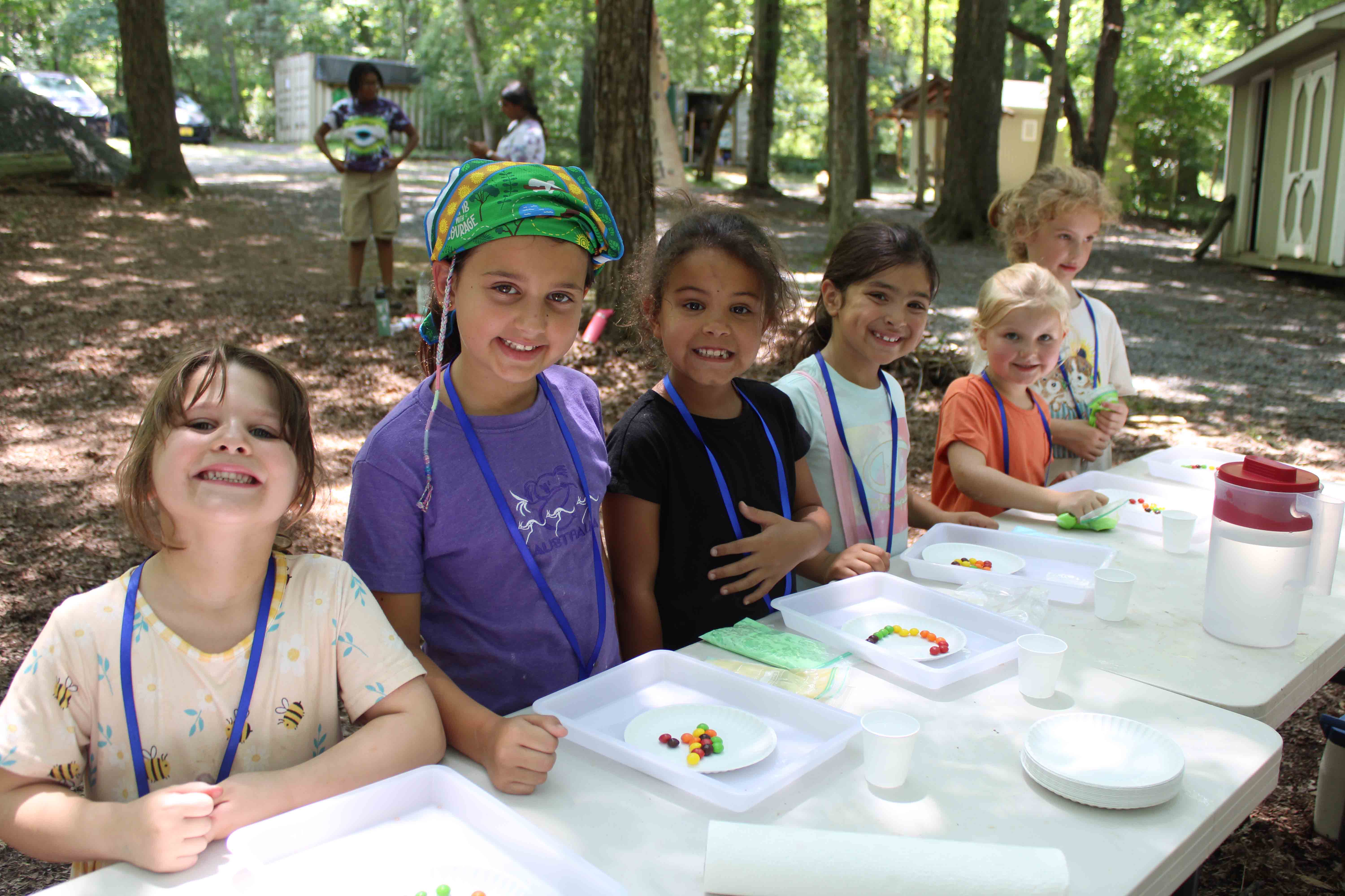 Campers focusing closely on a messy slime-making activity at the science station.