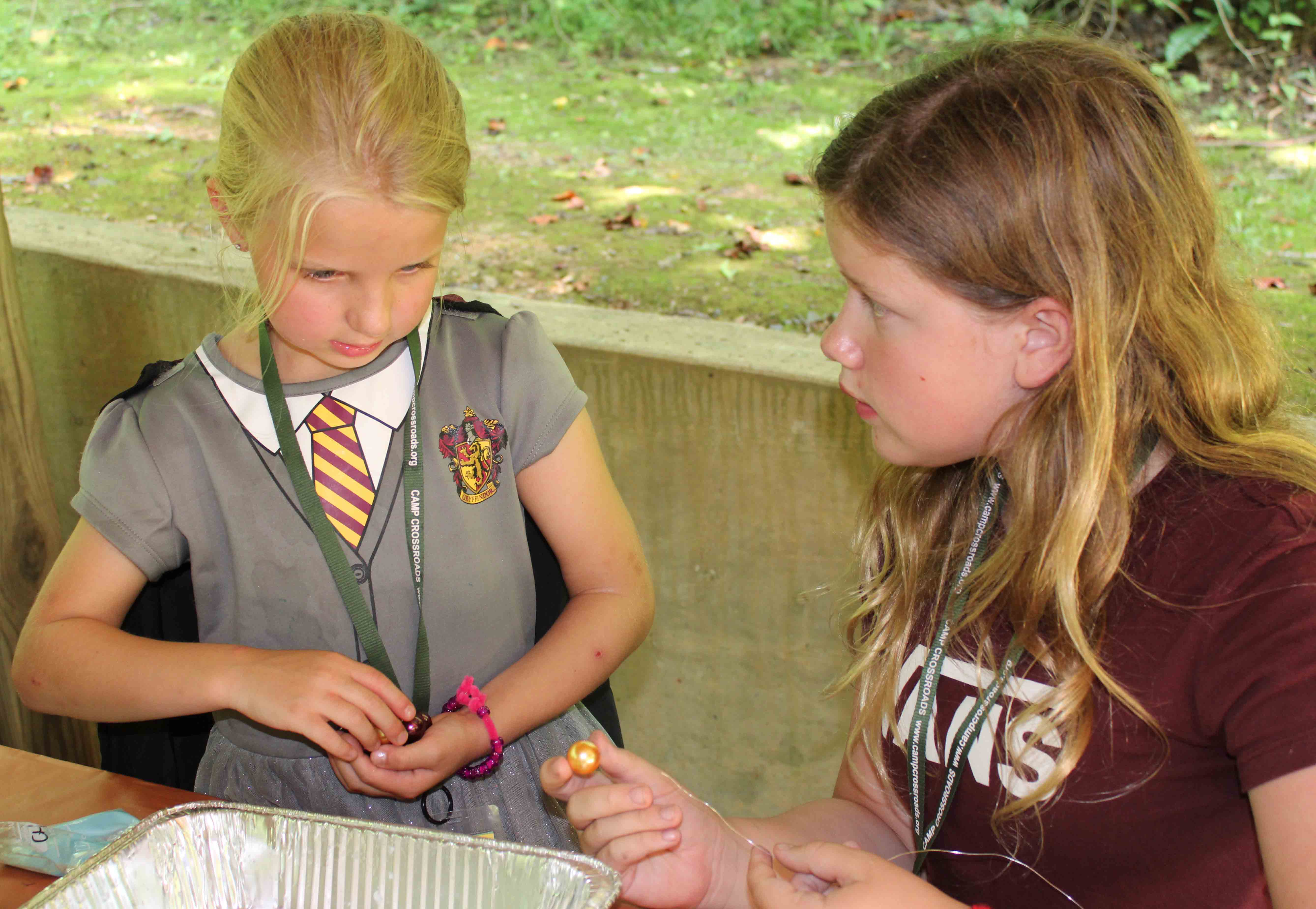 A young Pixie camper splashing and playing in a blue plastic wading pool on a hot day.