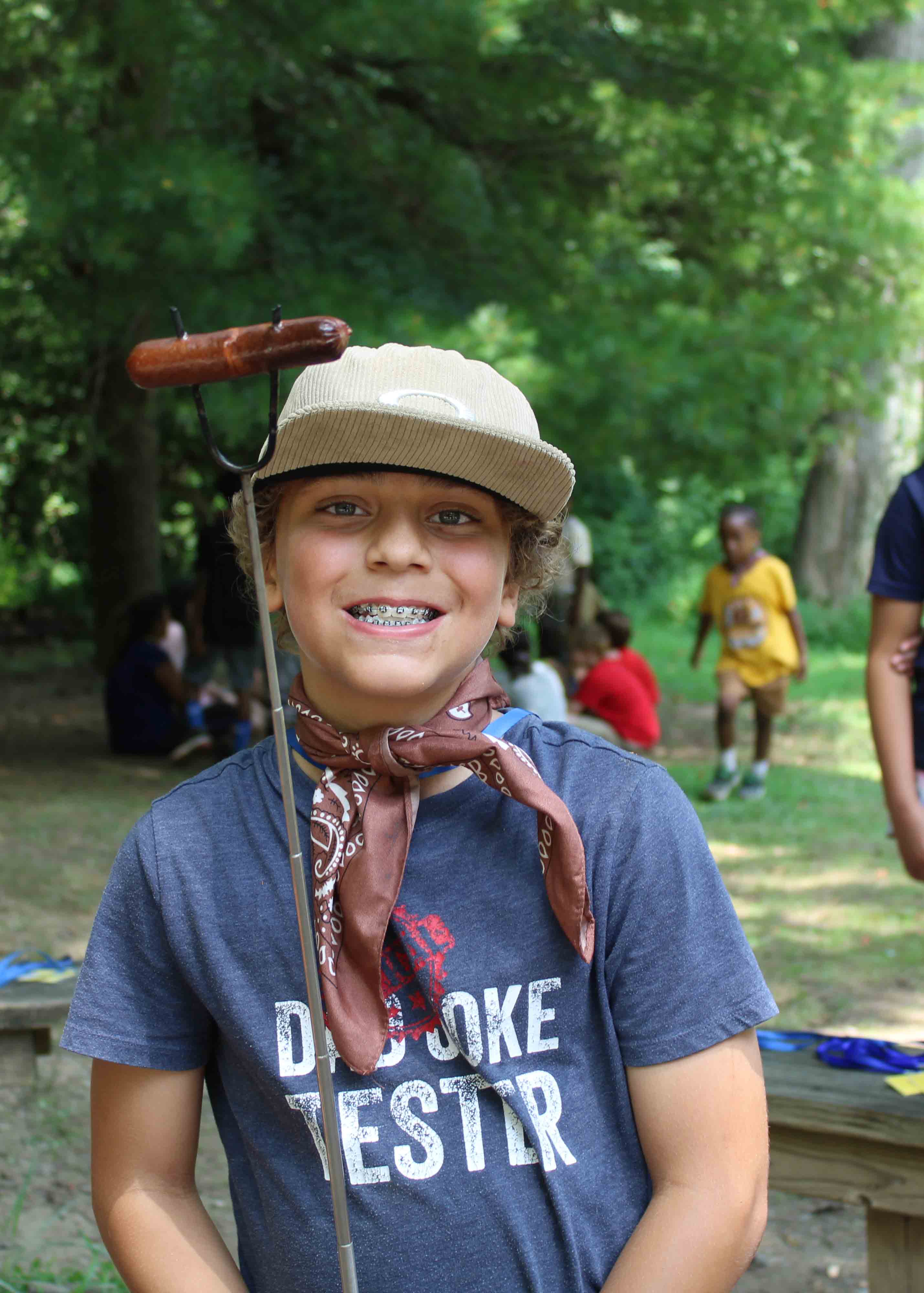 Campers holding onto a thick guideline as they walk across a low-ropes bridge.