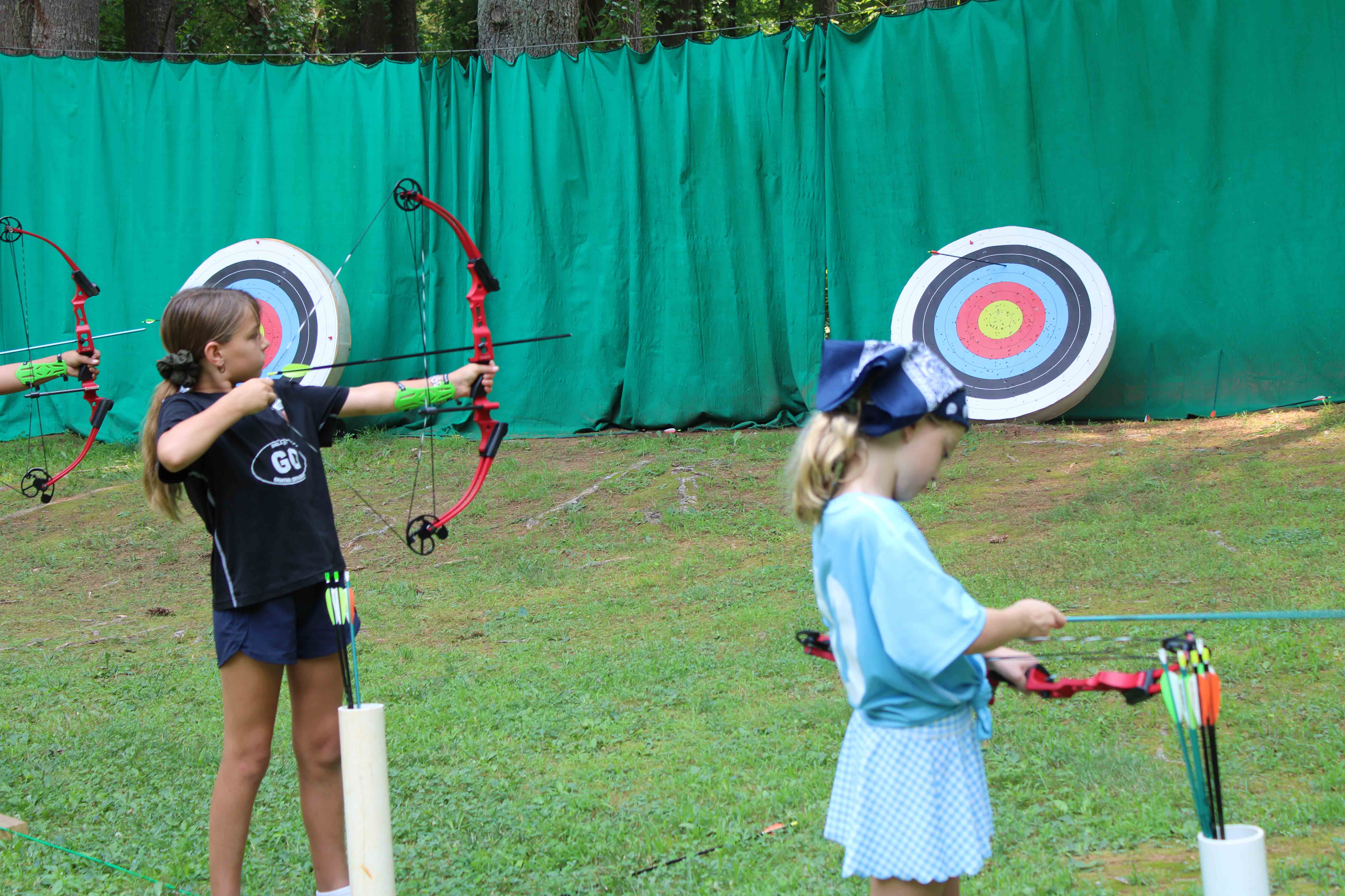 Campers lined up at the archery range taking aim at target boards.