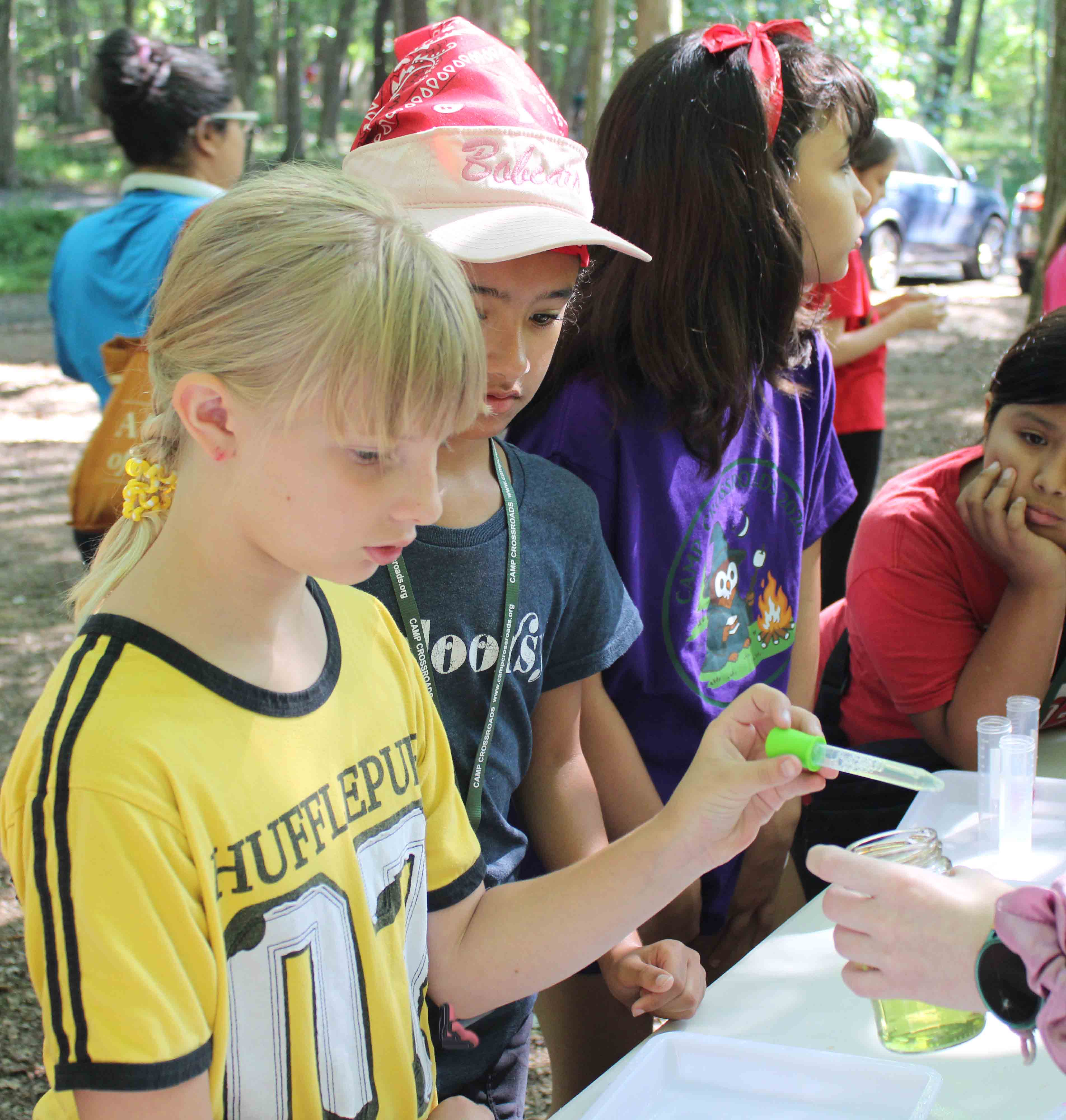 A camper using science tools and a dropper to mix colorful liquids during science.